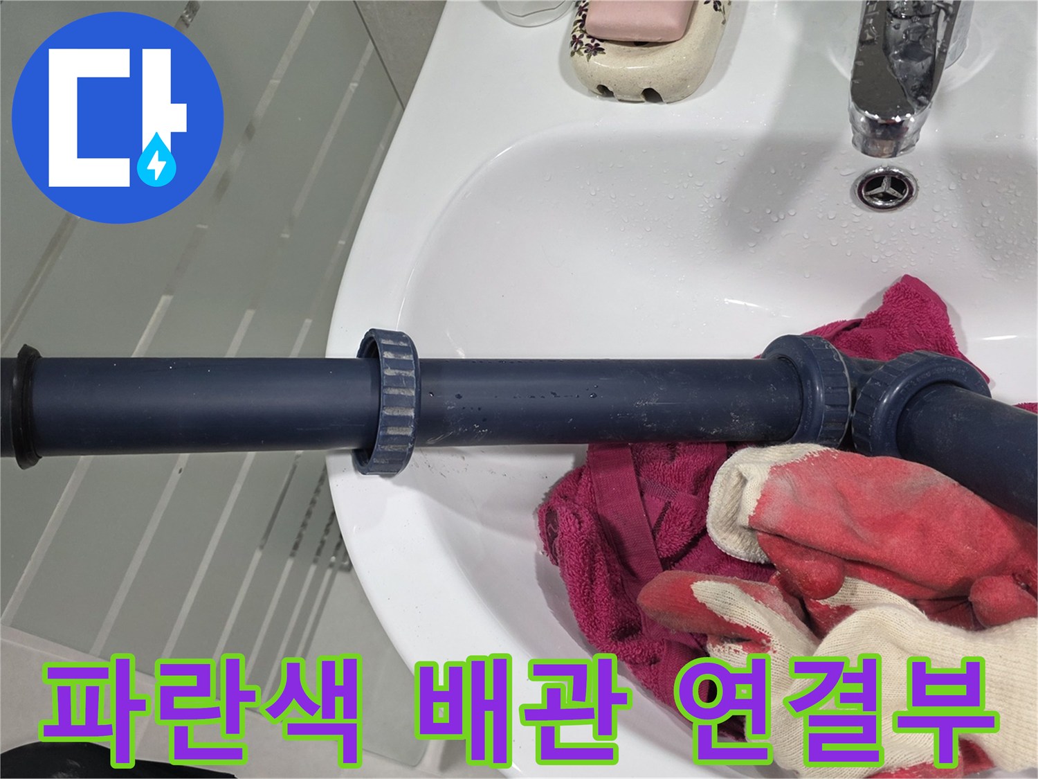 세면대 아래 파란색 오배수관과 작업용 장갑 사진입니다.