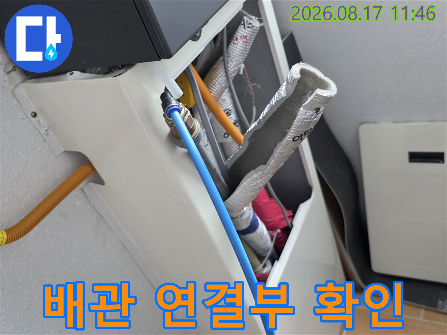 은박 보온재가 씌워진 배관과 파란색 호스의 연결 상태를 근접 촬영한 사진