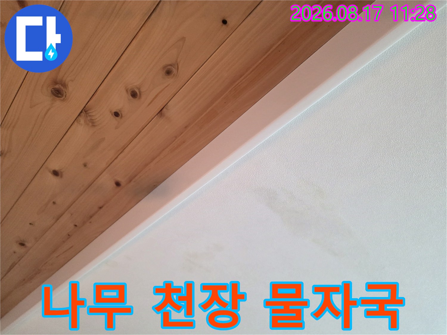 나무 판재와 흰색 벽면 경계의 누수 흔적 부위