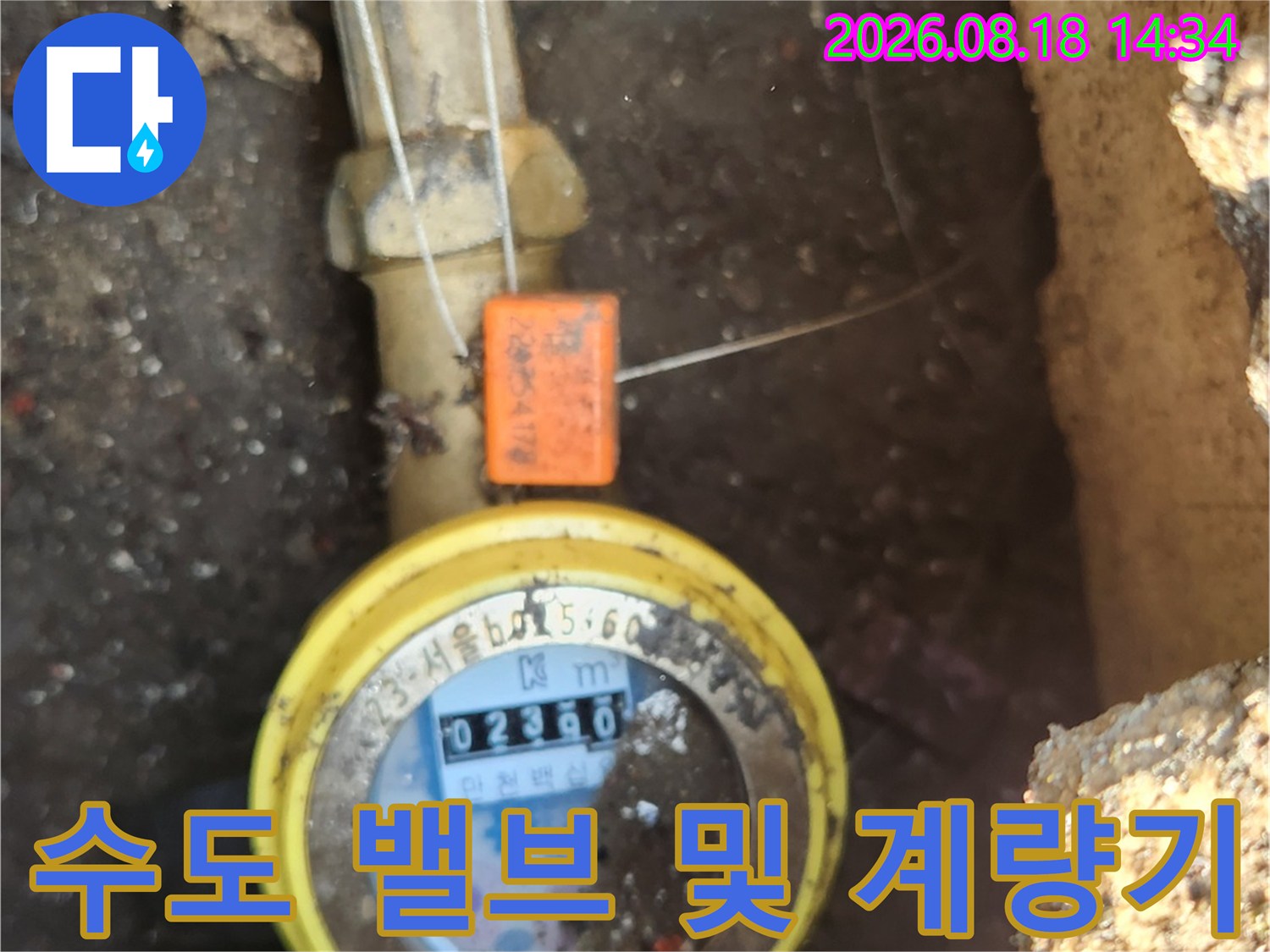 주황색 밸브와 노란색 수도 계량기가 연결된 배관 사진입니다.
