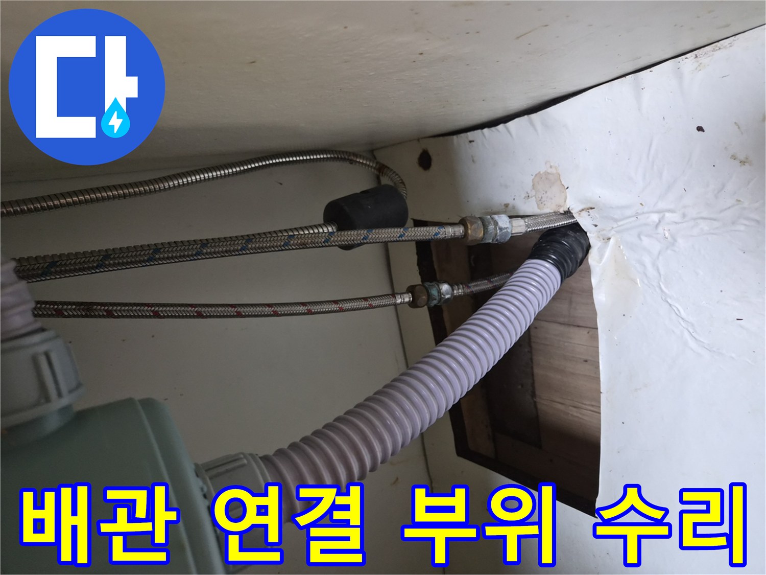싱크대 하부의 금속제 급수 호스와 흰색 유연한 관의 모습
