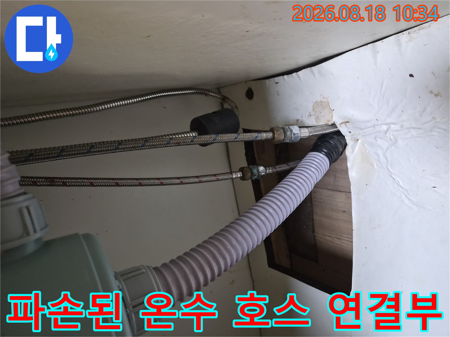 싱크대 하부장 내부의 금속 고압 호스와 굵은 배수 호스가 연결된 모습