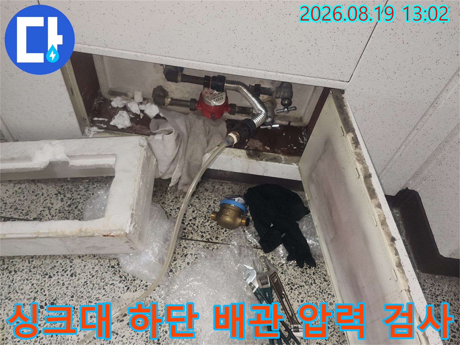 싱크대 하부 배관 연결 부위에 공압 장비를 연결하여 검사하는 모습입니다.