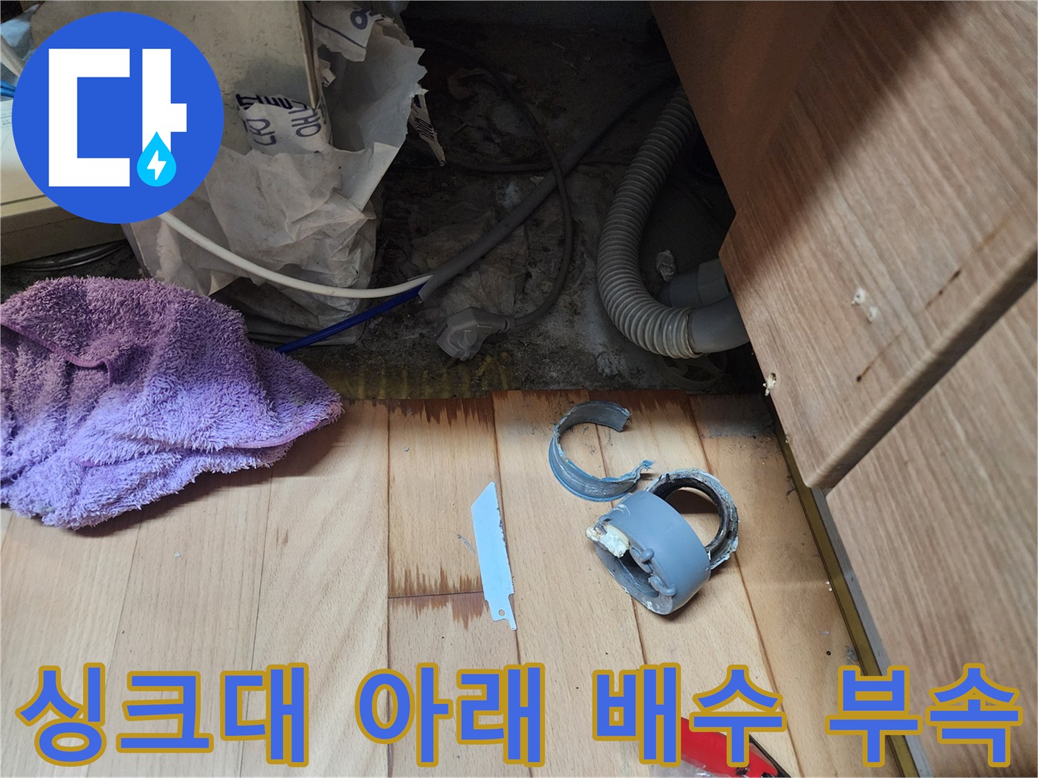 분리된 싱크대 배수 부속과 젖은 바닥재 사진