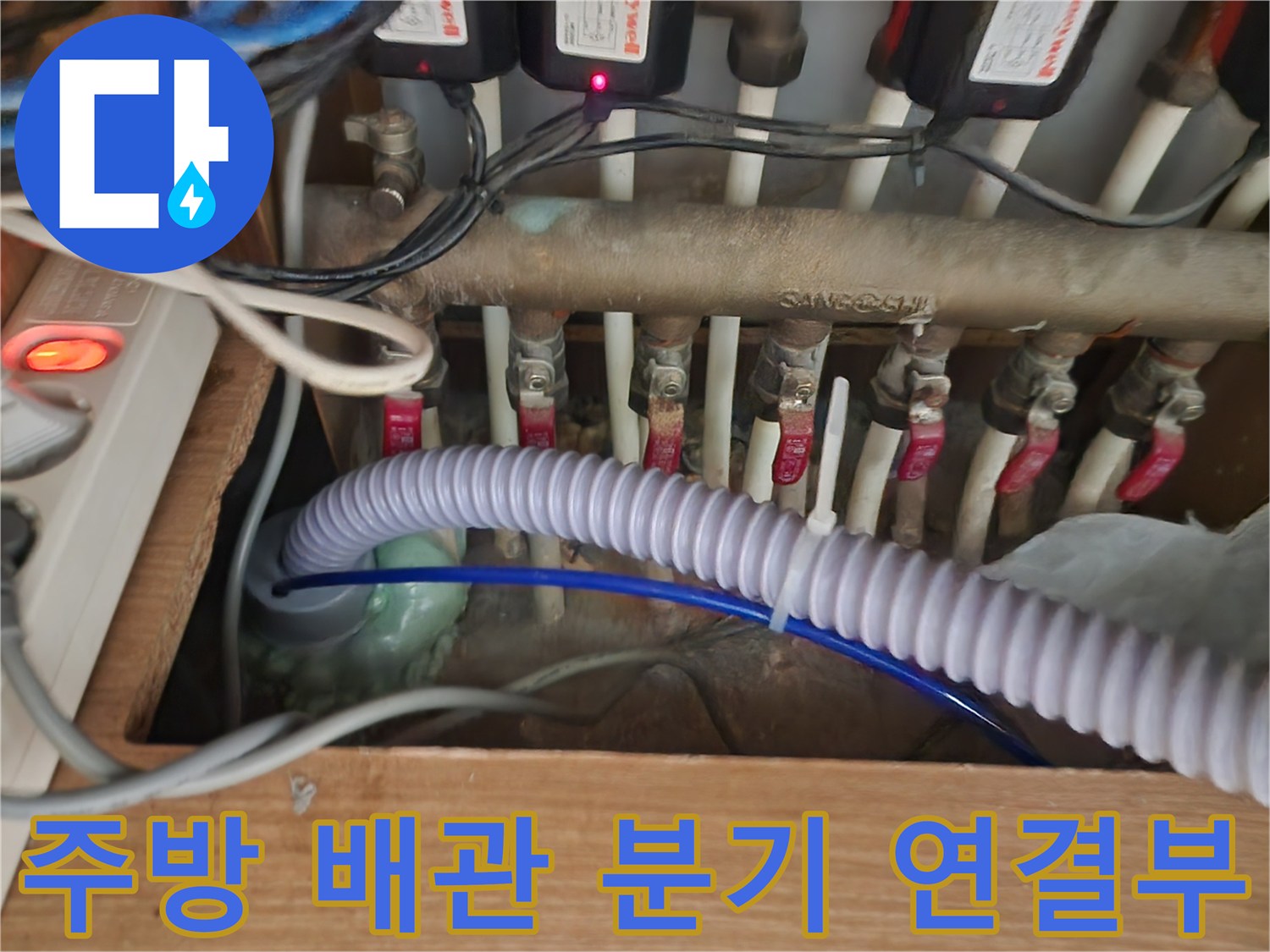 싱크대 아래 복잡하게 얽힌 배관과 제어 장치들