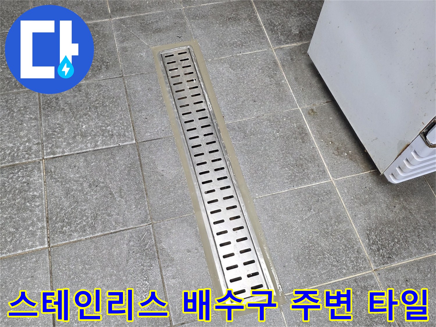 틈새가 벌어진 스테인리스 트렌치와 회색 바닥 타일