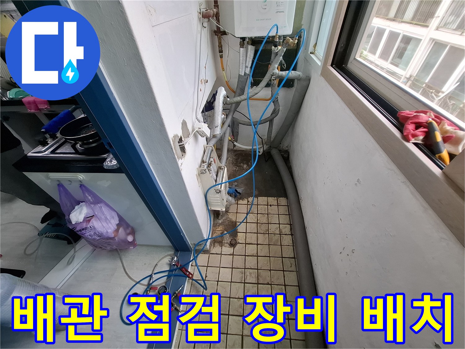 바닥 타일 위에 놓인 파란색 호스와 배관 연결 부위의 근접 촬영