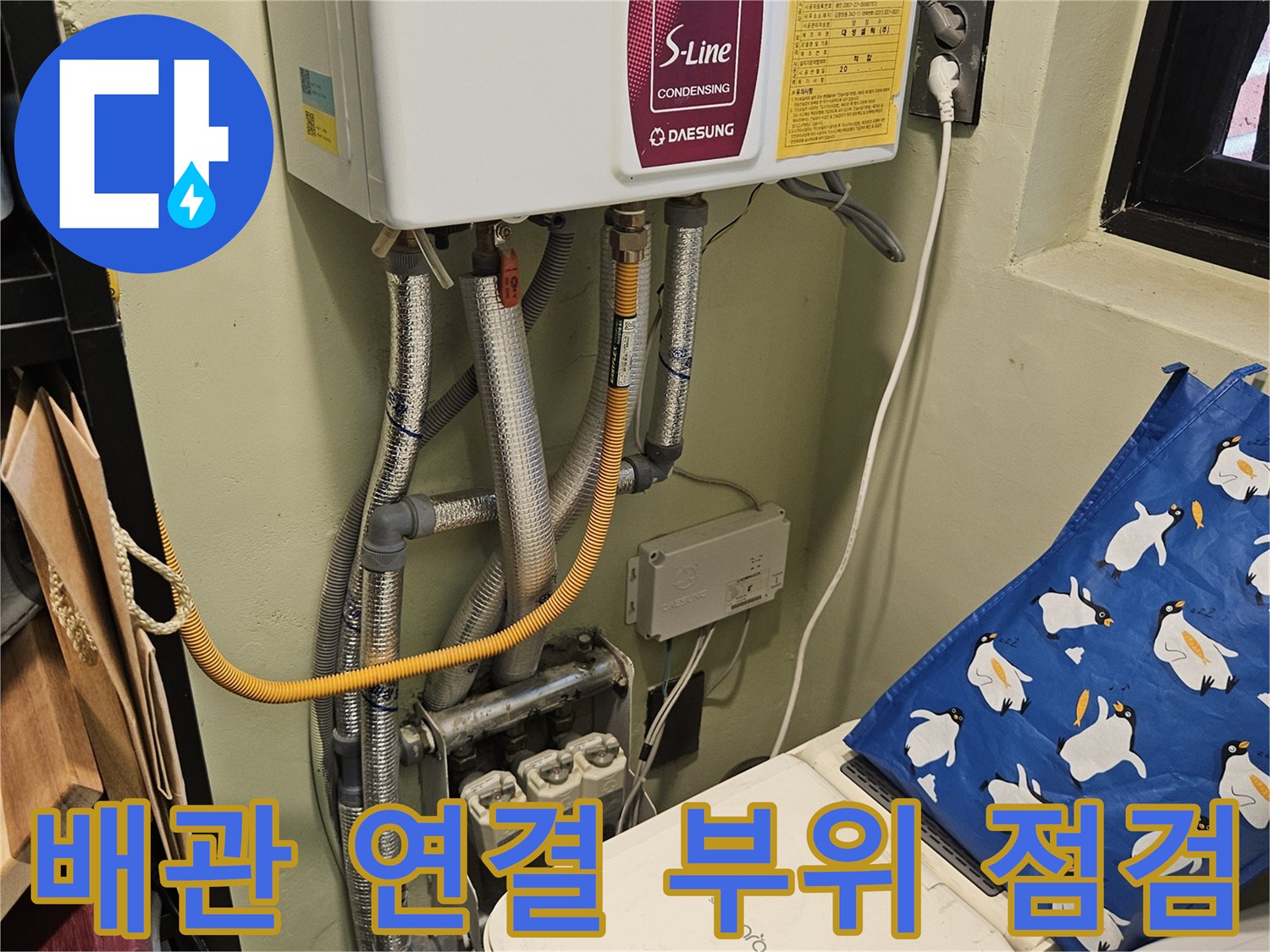 보일러와 연결된 은색 배관 및 벽면 콘센트 모습