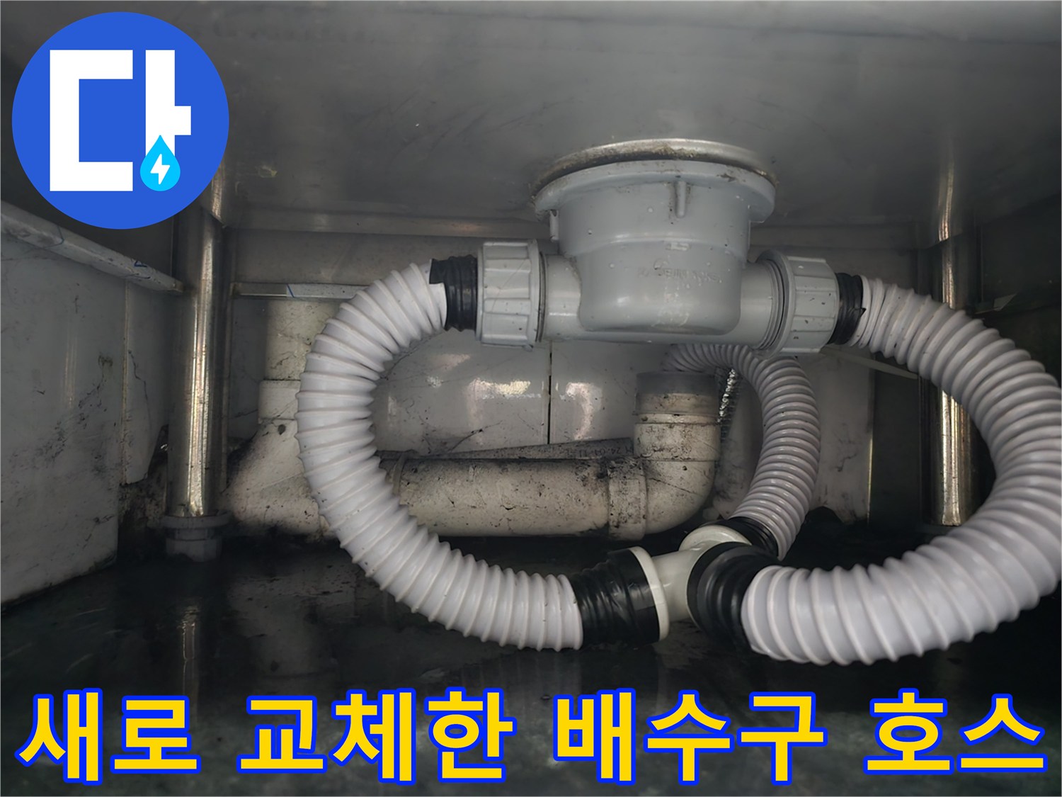 싱크대 하단에 설치된 깨끗한 상태의 배수용 주름관과 연결 부품입니다.