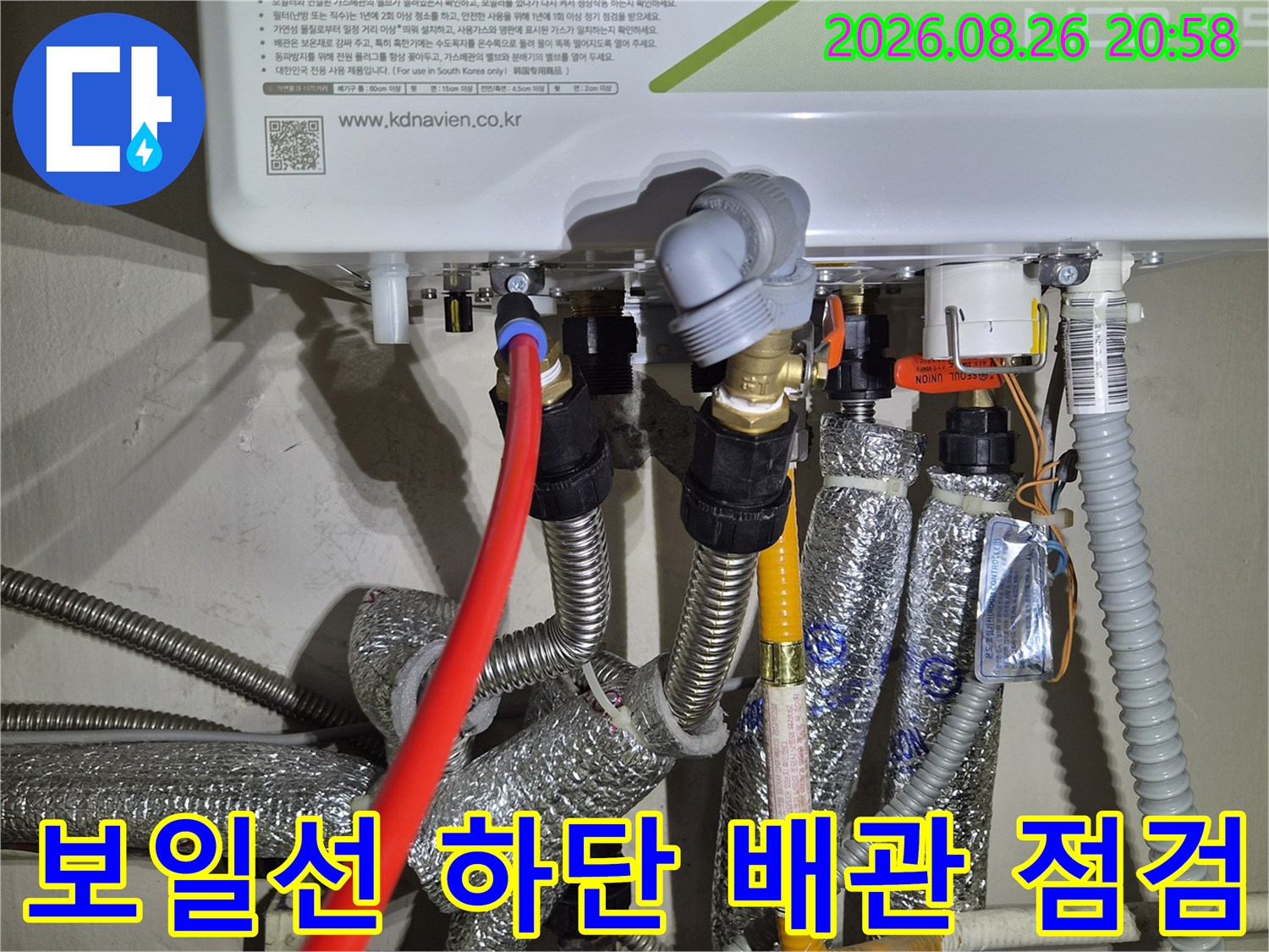 보일러 아래쪽 금속 배관과 보온재로 감싸진 연결 부위 모습