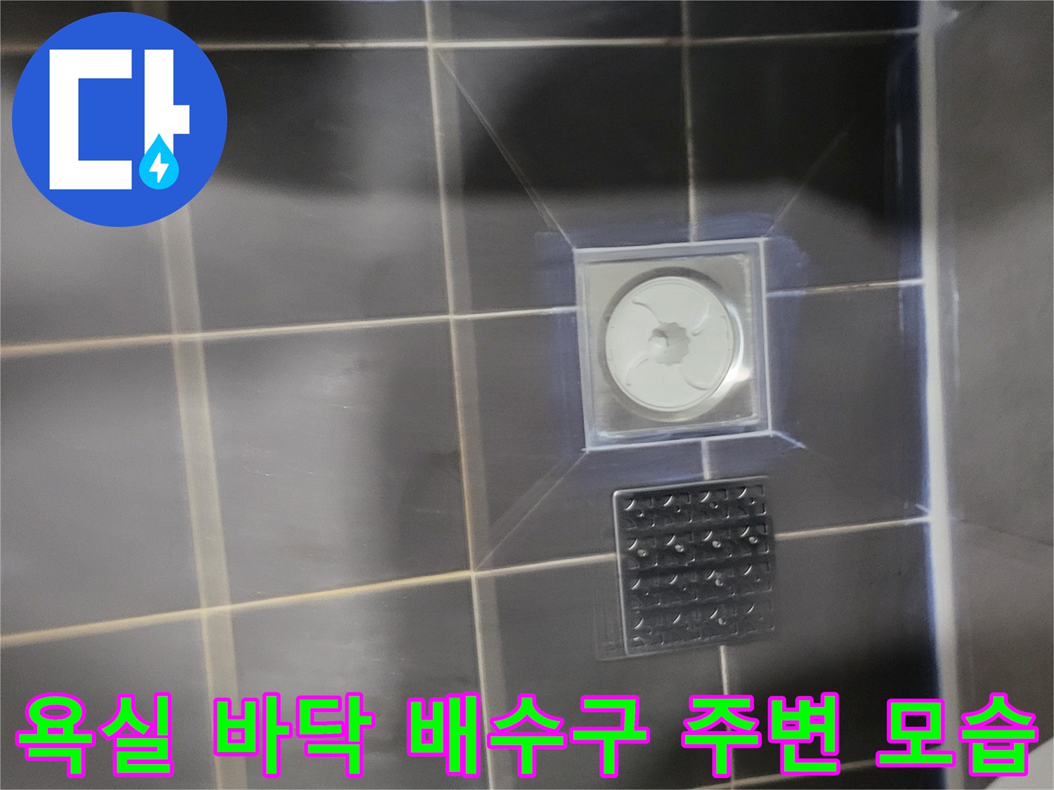 어두운 색 타일과 흰색의 배수구 부속품 부위