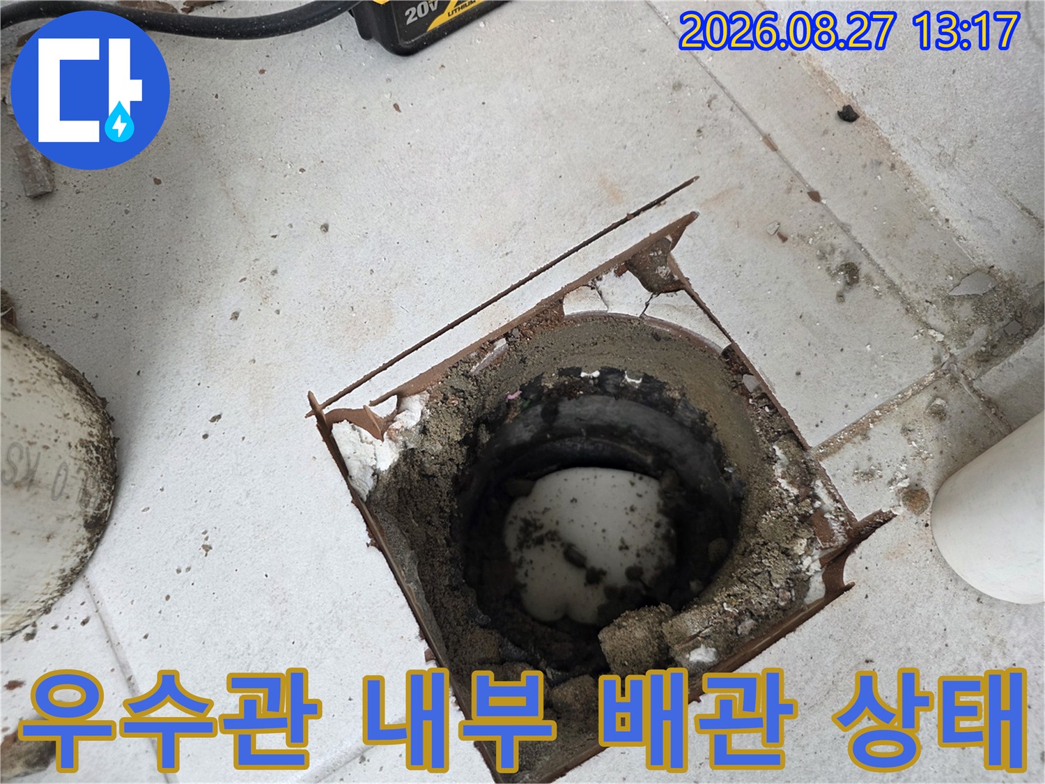 배관 주변의 파손된 금속 프레임과 흙이 섞인 마감재