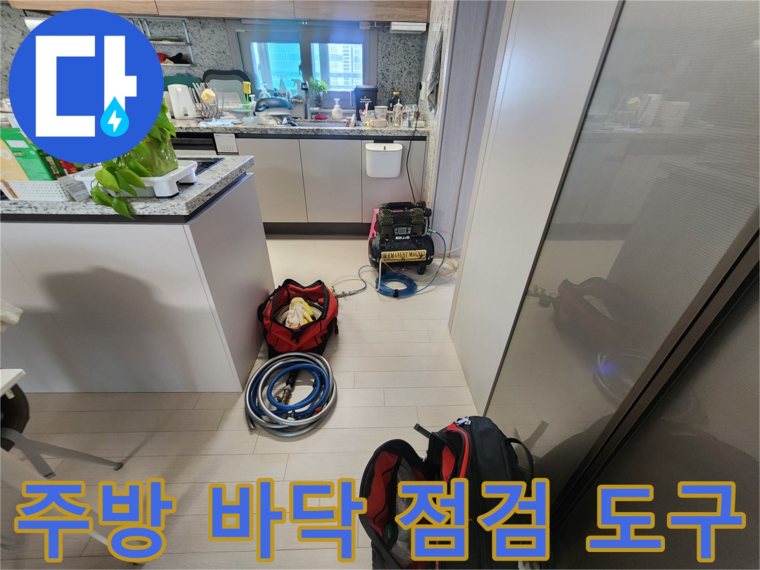 싱크대 밑 공간에 놓여 있는 파란색 호스와 수압 측정 장비