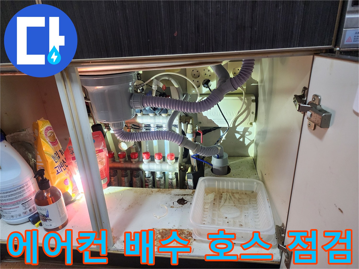 싱크대 밑 자색 에어컨 배수 호스와 연결된 다수의 배관들