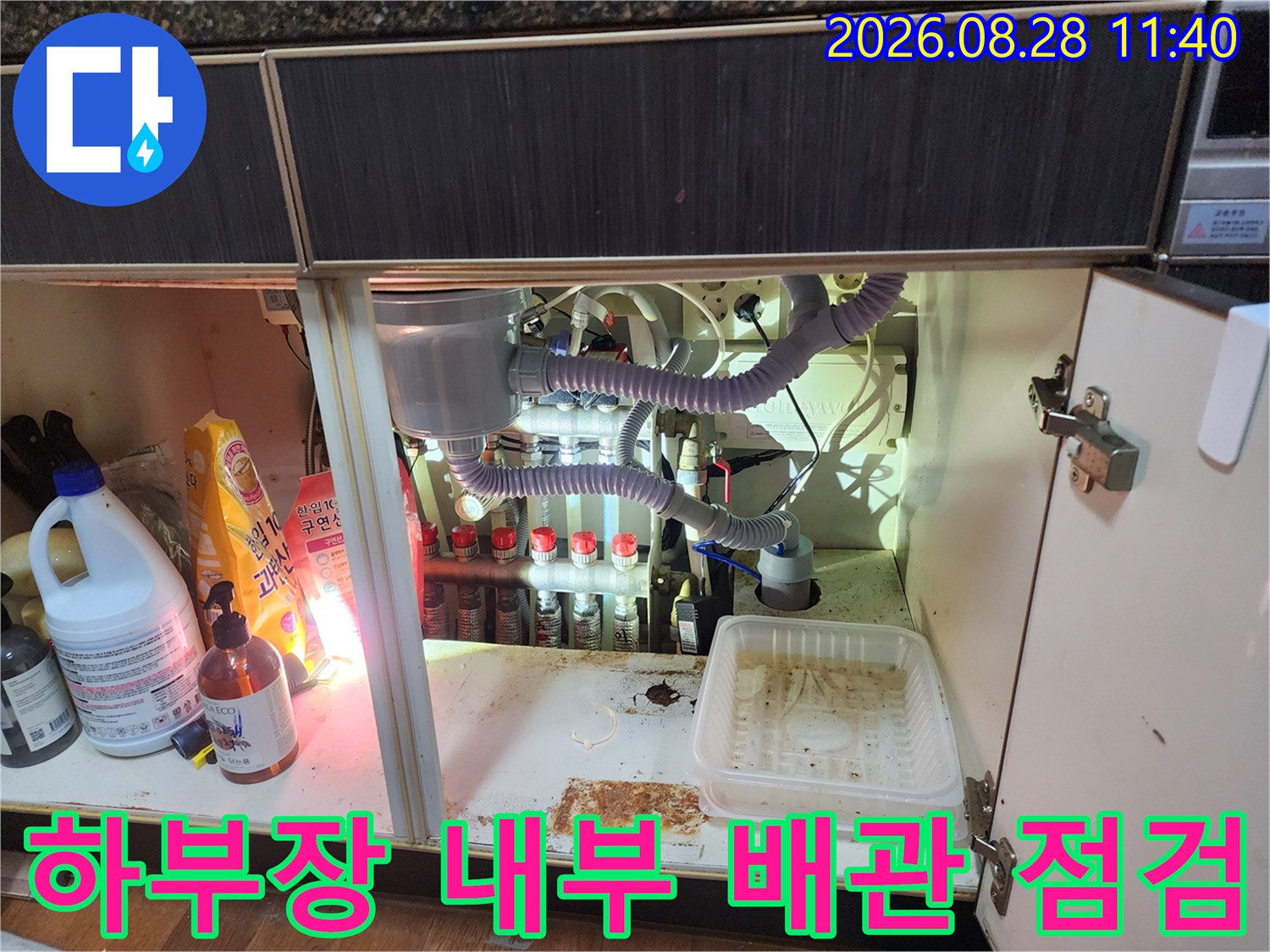 싱크대 하단 배관과 에어컨 드레인 호스가 복잡하게 얽혀 있는 모습입니다.