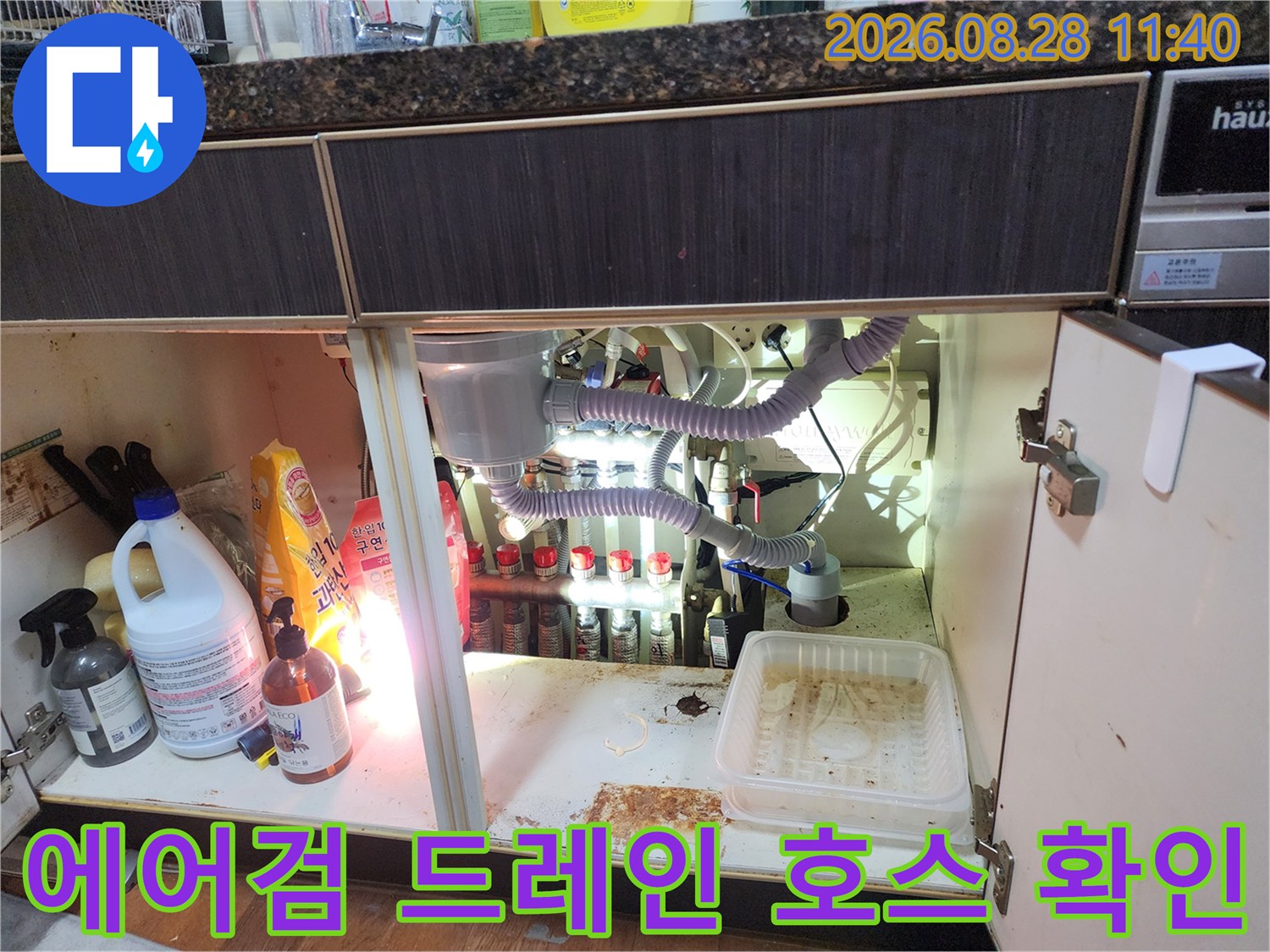 싱크대 하단 배관의 에어컨 응축수 드레인 호스 연결 상태와 주변 환경