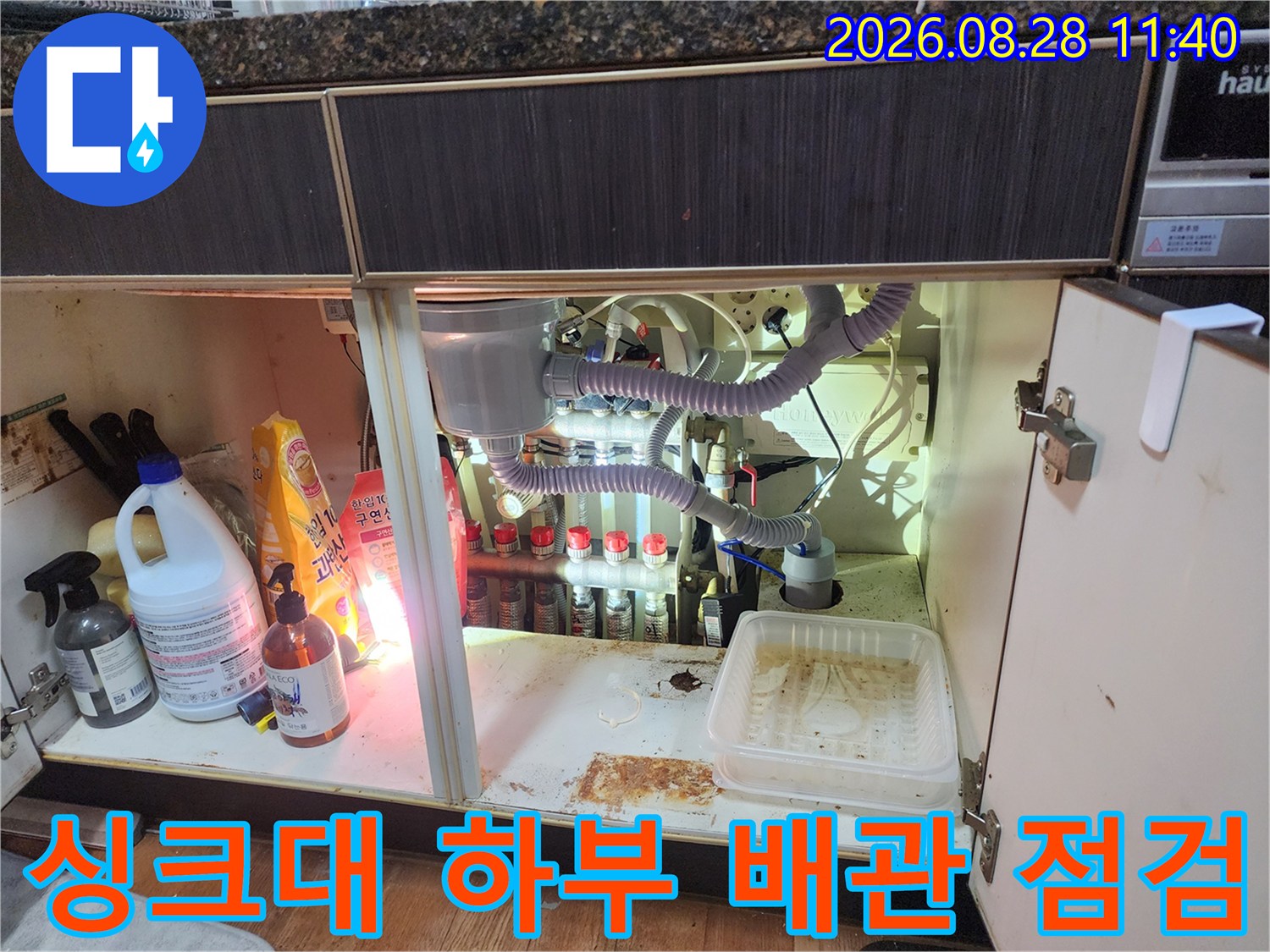싱크대 하부장 내부의 에어컨 드레인 호스와 다수의 배수 배관들