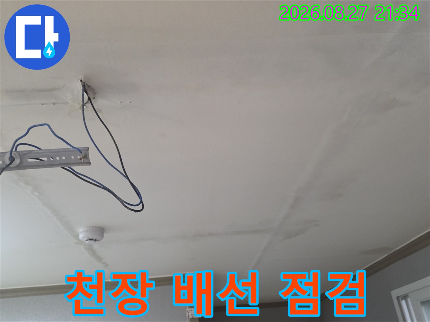 천장의 누수 흔적과 노출된 금속 지지대 및 전선