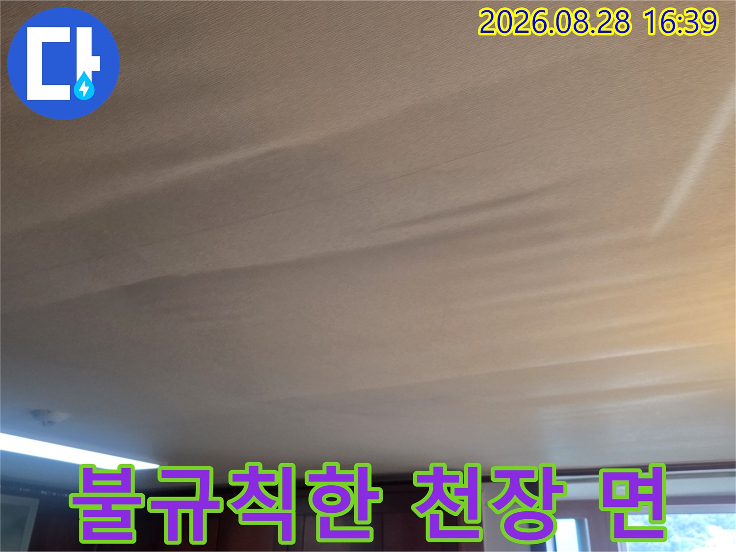 천장 벽지가 물기에 젖어 불룩하게 튀어나오고 처진 상태를 보여줍니다.