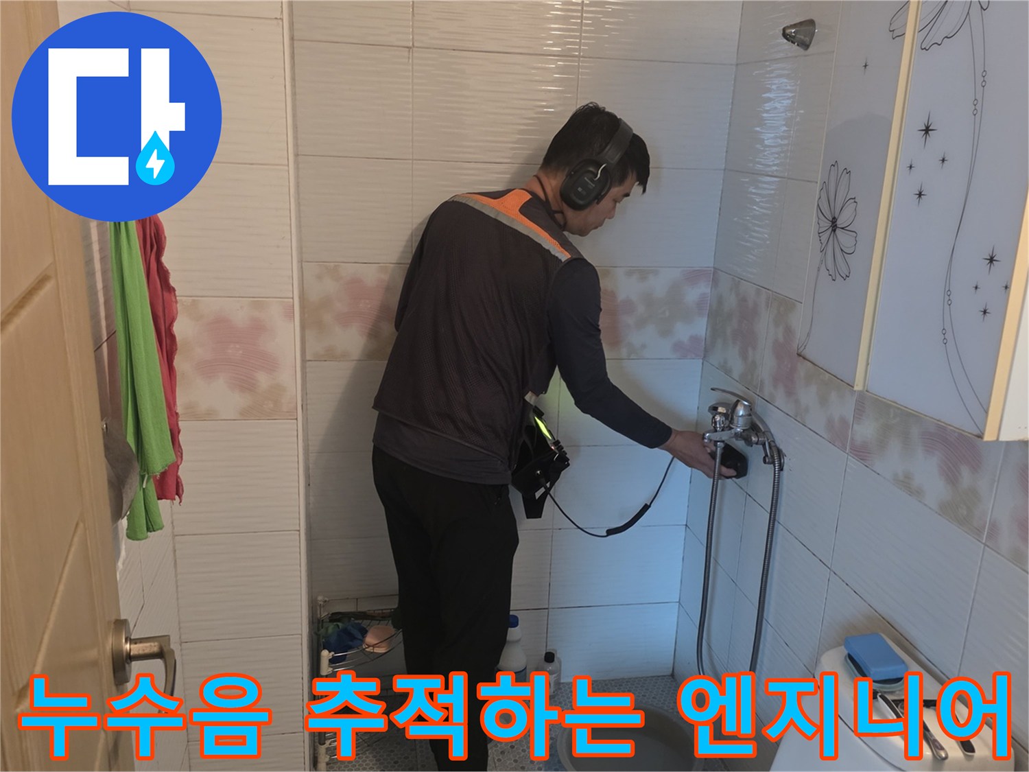 헤드폰형 탐지기를 사용하여 세면대 하단 배관의 물소리를 찾는 현장 모습
