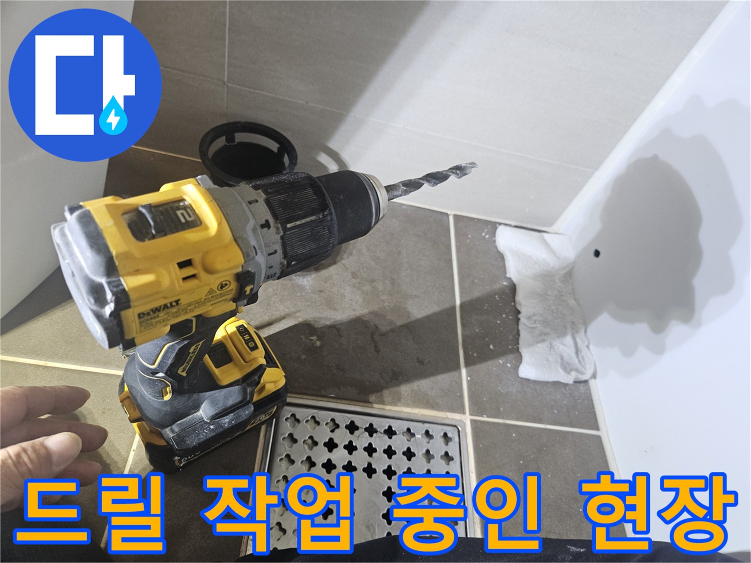 전동 드릴을 사용하여 타일 벽면을 뚫고 있는 공사 장면