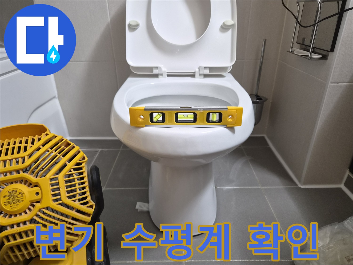 변기 위에 놓인 노란색 수평계와 작업용 송풍기