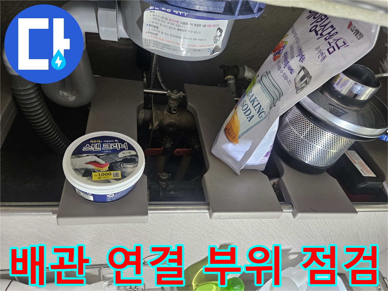 싱크대 하단 배수 호스와 수도 관련 부속품들의 배치