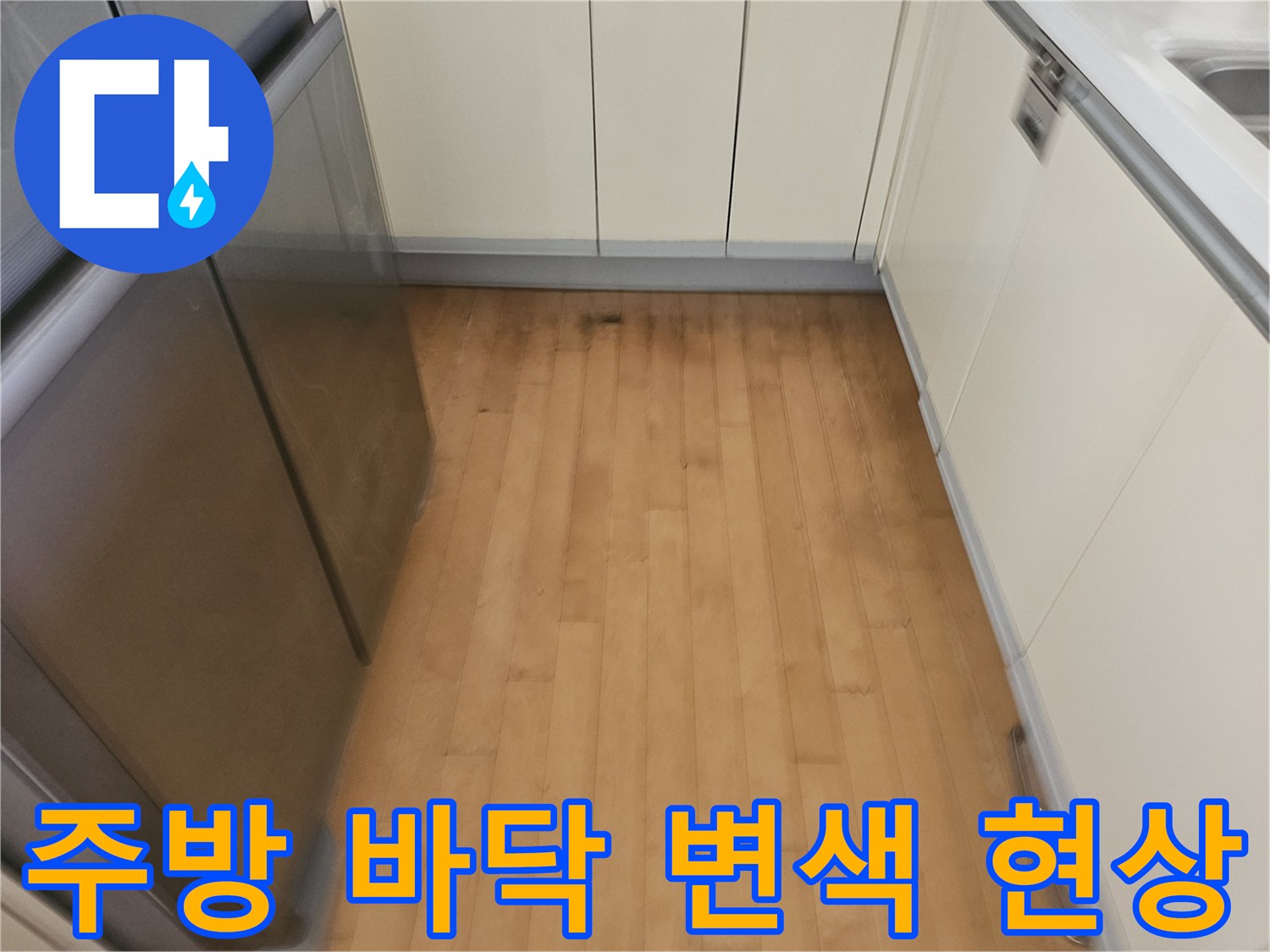 싱크대와 냉장고 사이 바닥 마감재의 어두운 얼룩과 습기 흔적