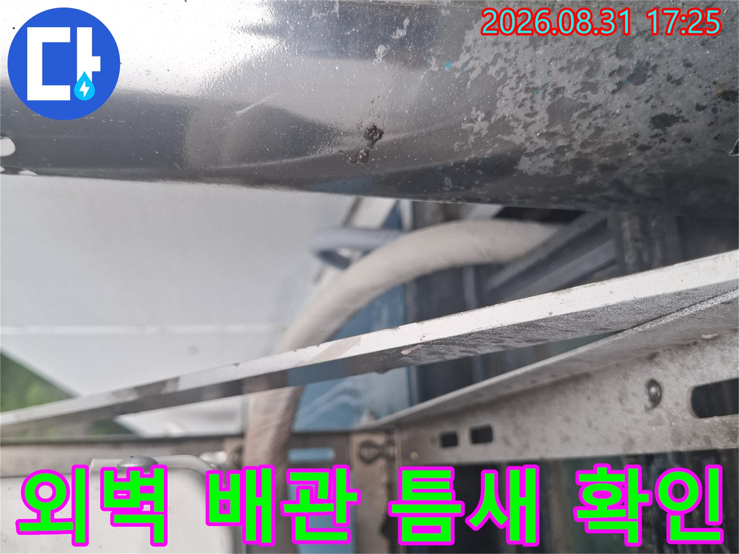 금속 배관 구조물과 에어컨 배관이 만나는 지점을 근접 촬영한 사진입니다.