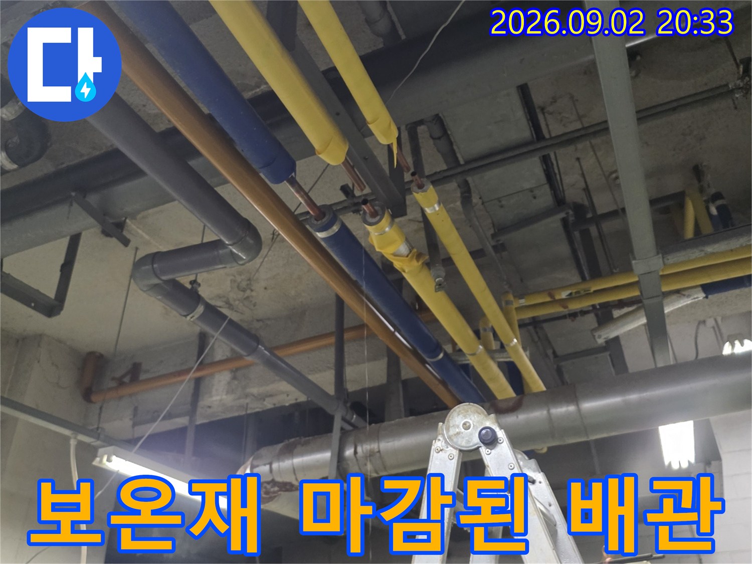천장 배관 점검 현장-노란색과 파란색 보온재로 덮인 배관 구조물