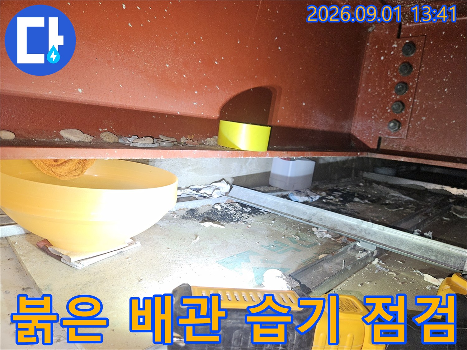 천장 구조물 아래에 위치한-붉은색 배관의 상태를 근거리에서 촬영했습니다.