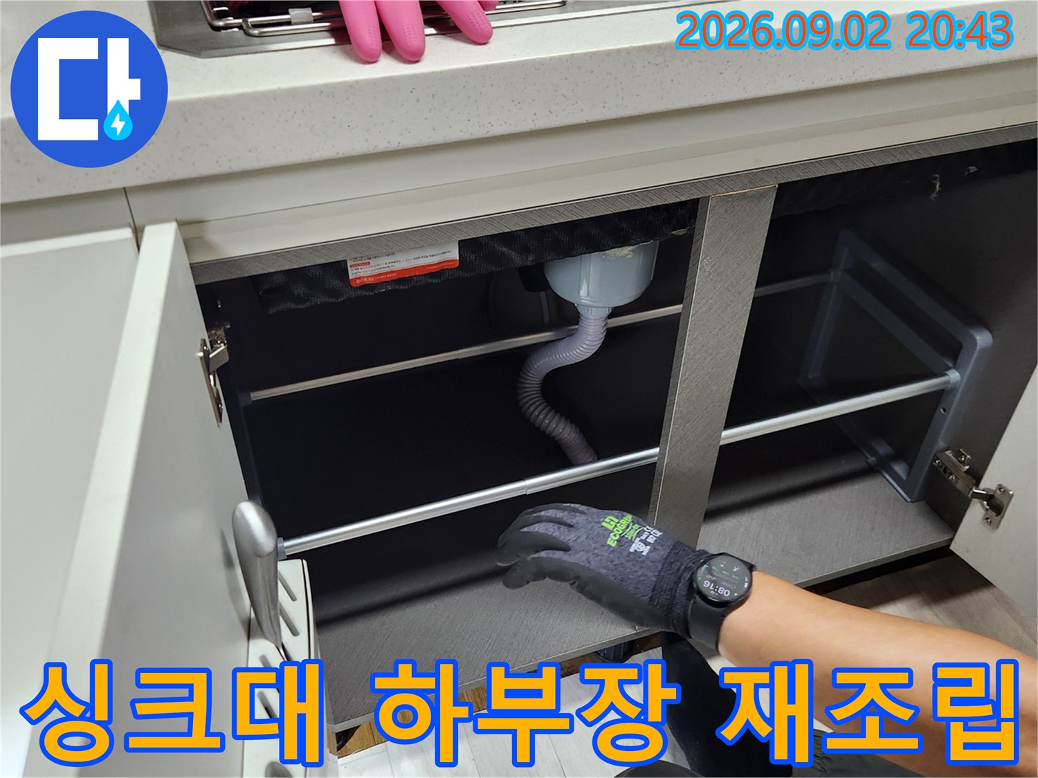 정리 완료된 싱크대 내부의 배수 호스와 선반 구조물