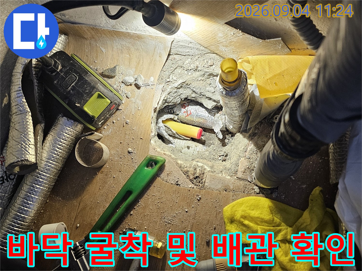 누수 지점 파악을 위해 타일을 깨고 배관을 드러낸 공사 현장입니다.
