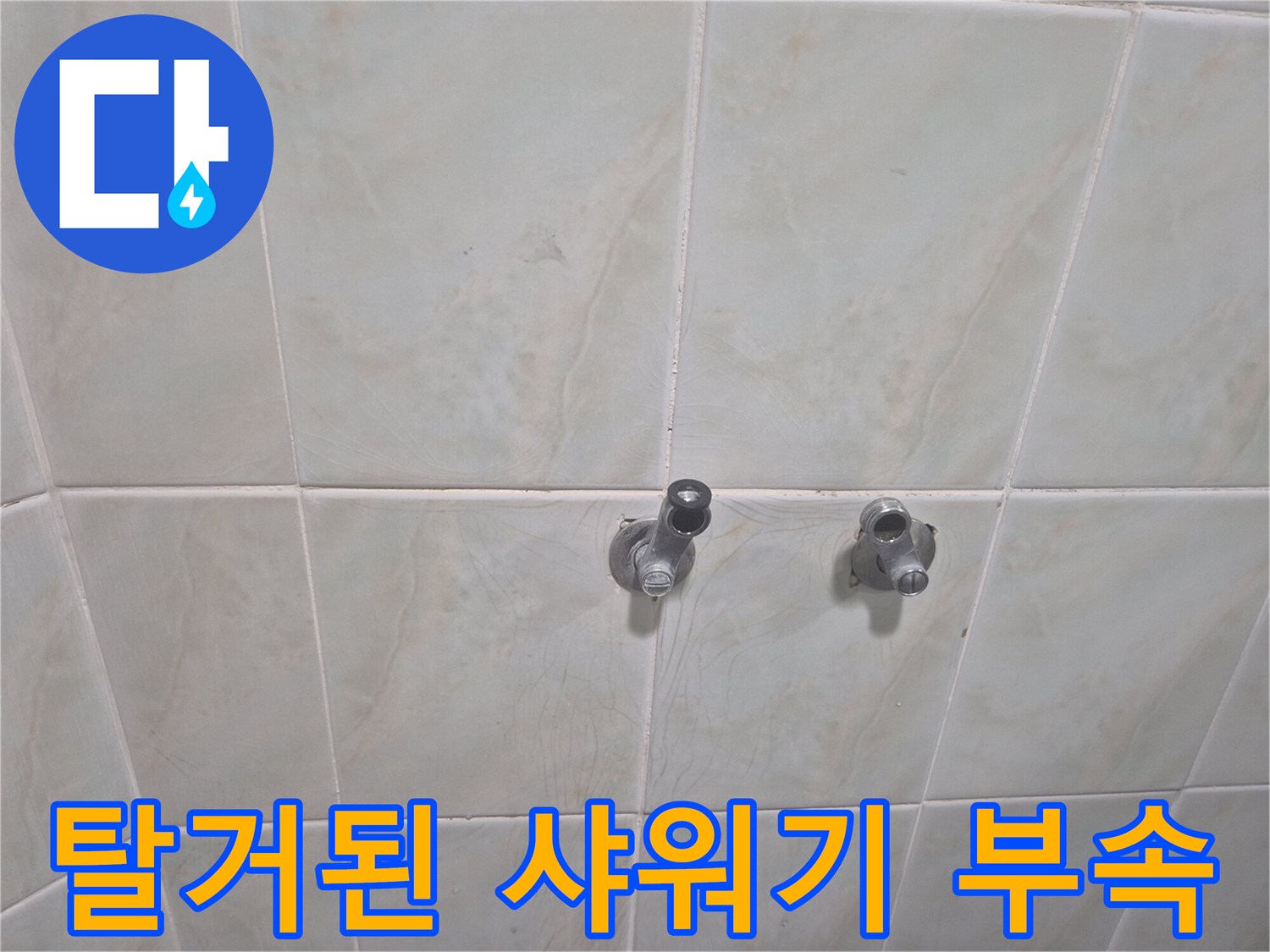 타일 벽면에 남은 수전 연결 배관과 제거된 부품의 모습입니다.