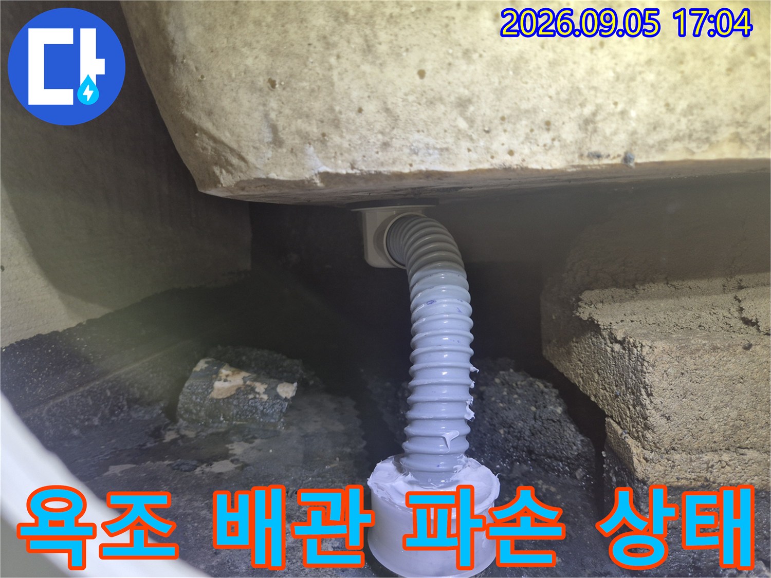 욕조 하부의 구불구불한 주름 배관과 파손된 연결 부위 모습