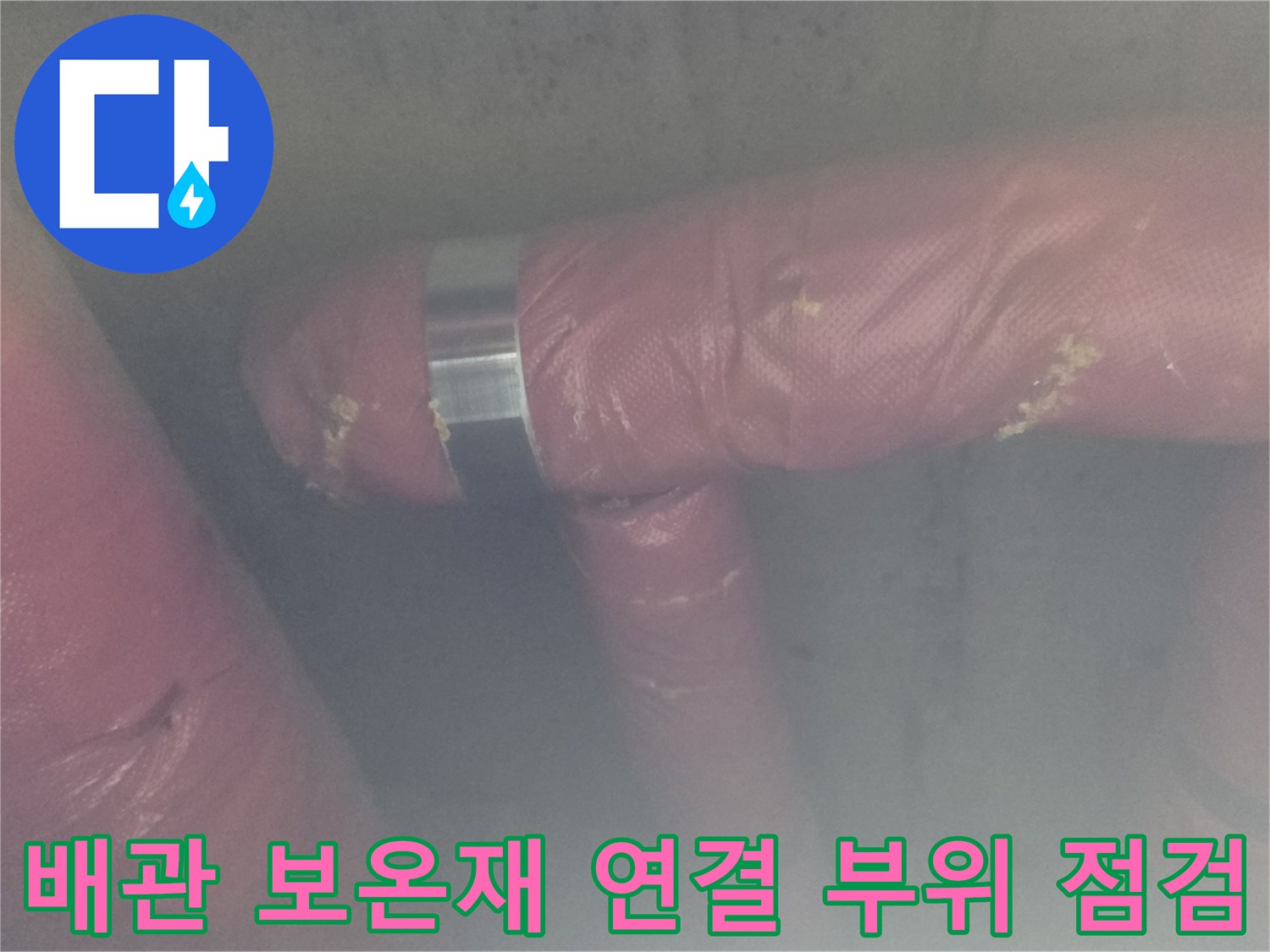 분홍색 보온재로 덮인 배관의 금속 밴드 결합부를 점검하는 엔지니어