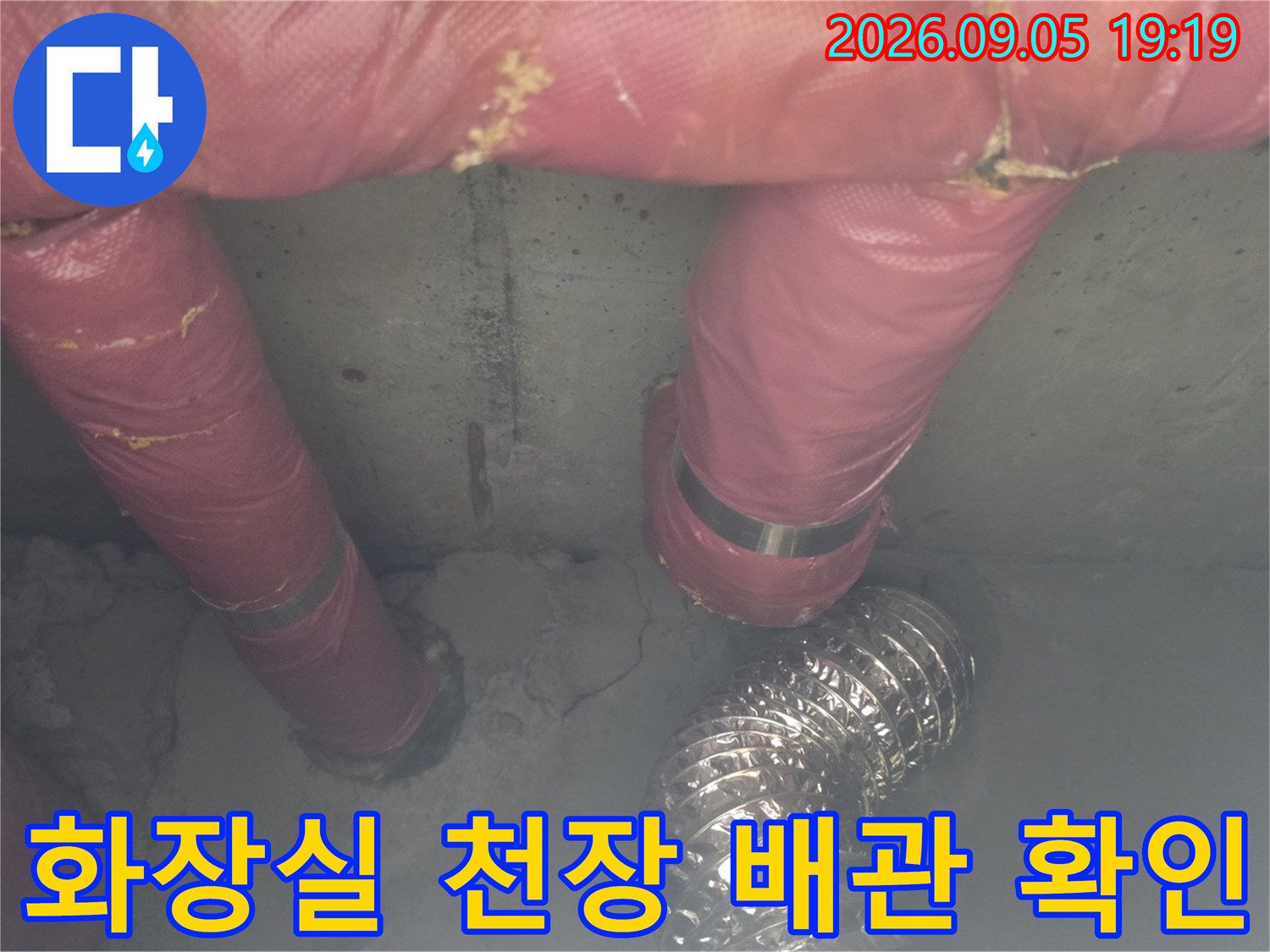 천장 점검구 안쪽의 분홍색 보온재 배관과 은색 자재 모습