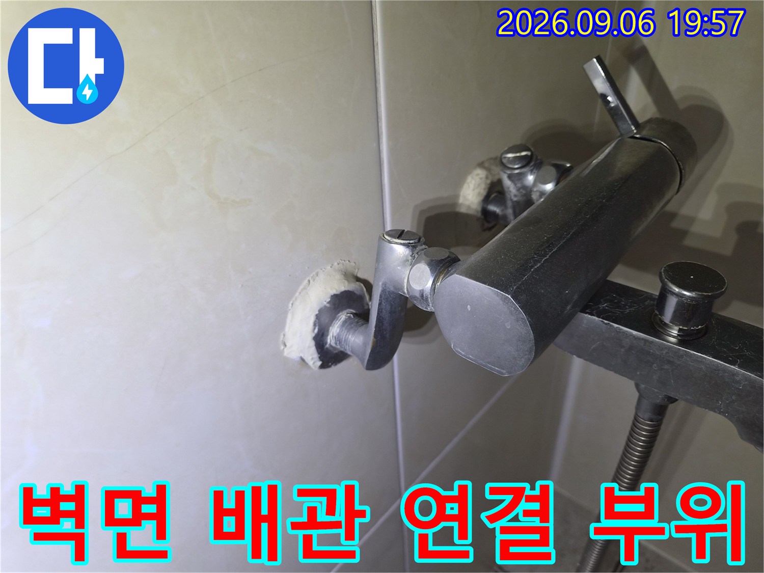 세면대 수전 뒤쪽 벽면에 노출된 배관 연결 부속의 근접 촬영 사진입니다.