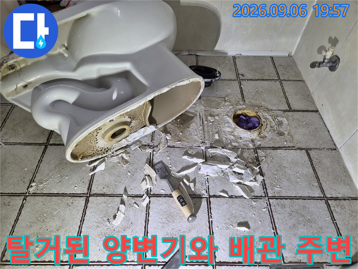 양변기를 탈거하여 드러난 오수관과 파손된 타일 조각들입니다.