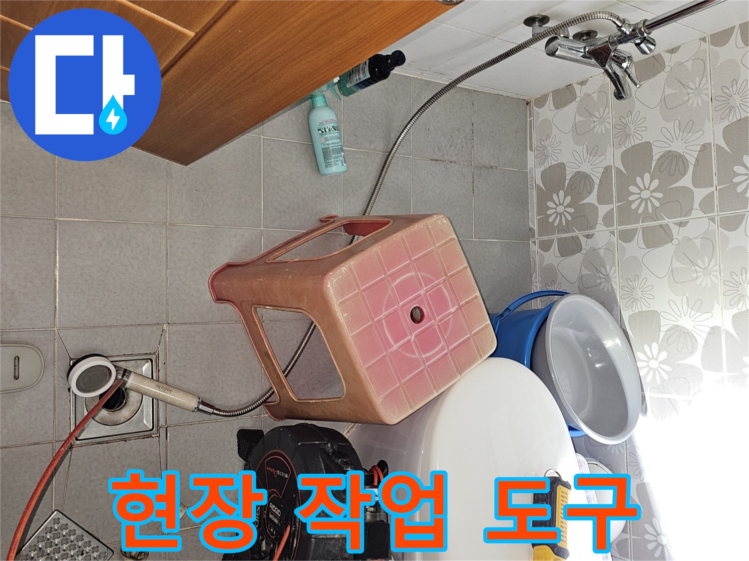 변기 옆에 놓인 드릴과 배관 점검용 릴 호스