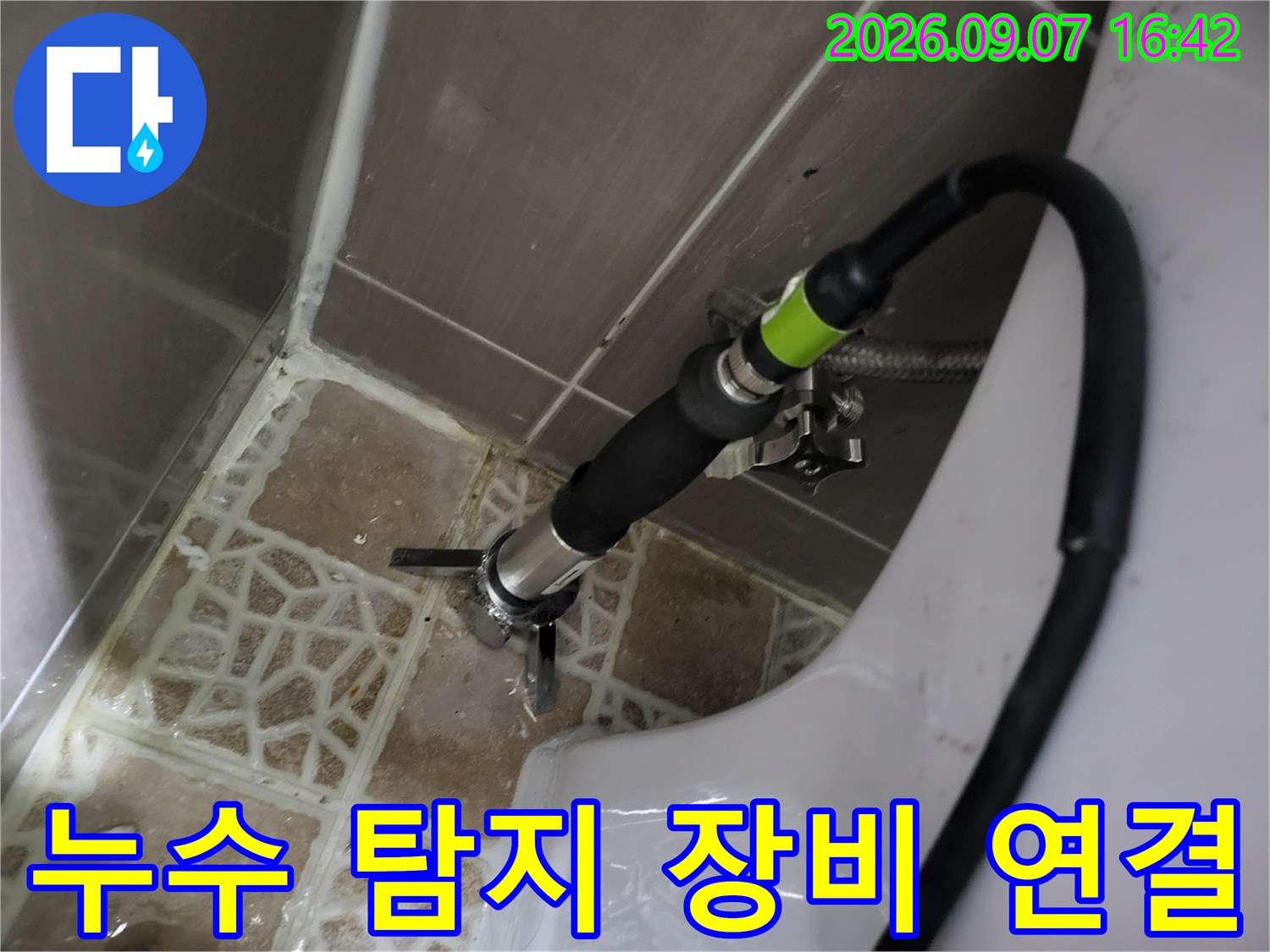 검사용 호스를 배관 부속에 연결하여 압력을 측정하는 장면입니다.