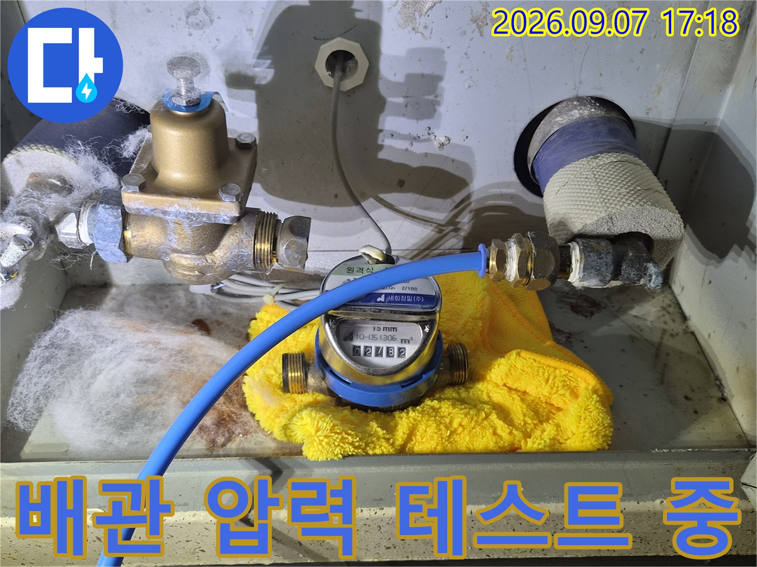파란색 호스와 연결된 압력계를 통해 배관의 기밀 상태를 측정하고 있습니다.
