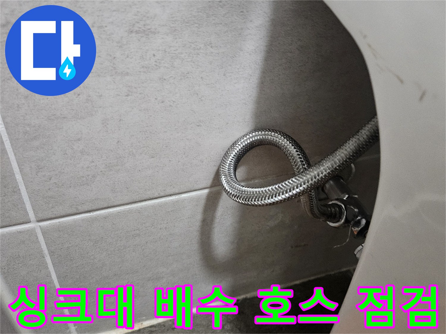 은색 자바라 형태의 싱크대 배관과 회색 타일 바닥면