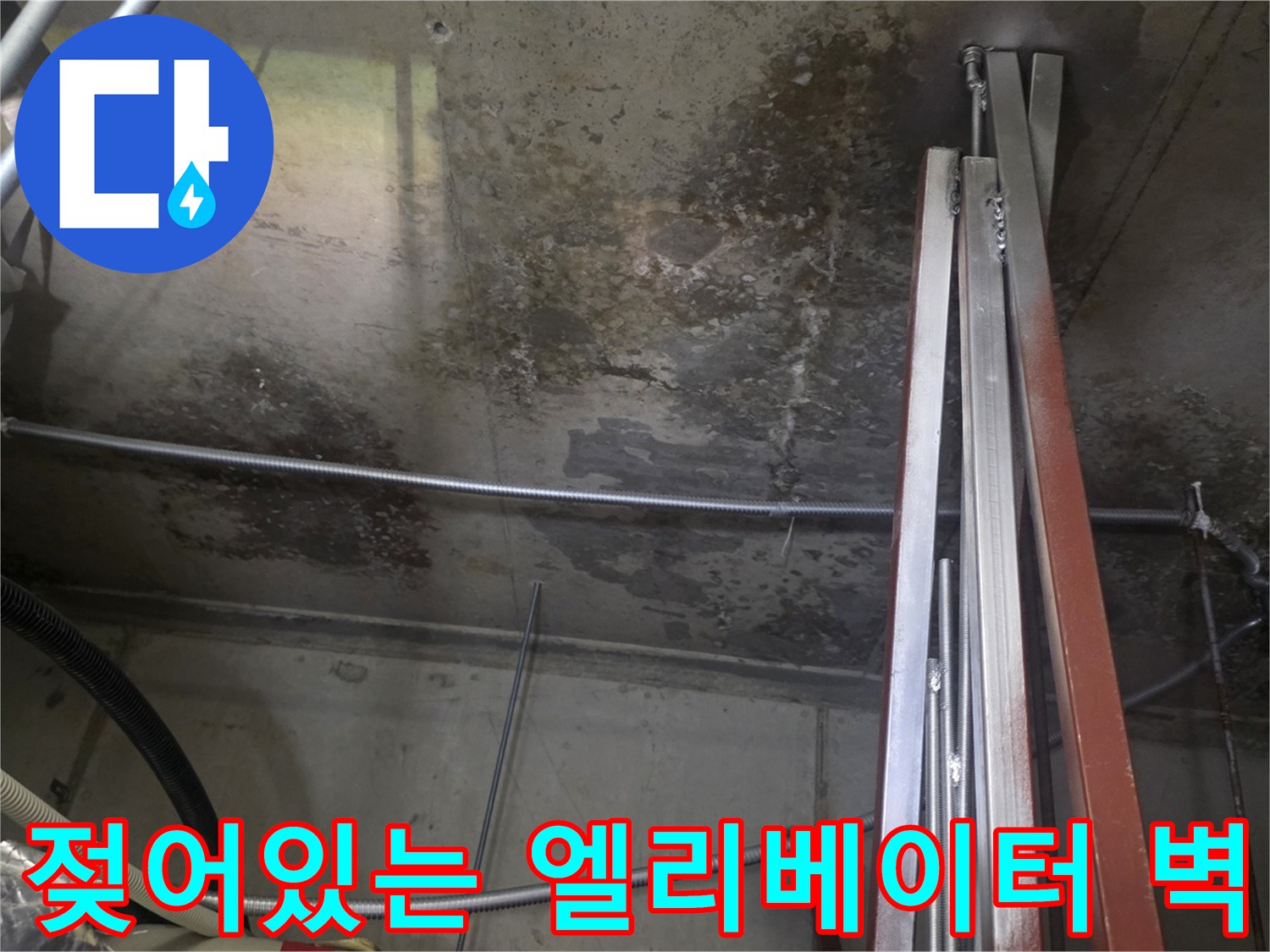 습기로 인해 얼룩진 엘리베이터 내부의 콘크리트 및 배관 구조물