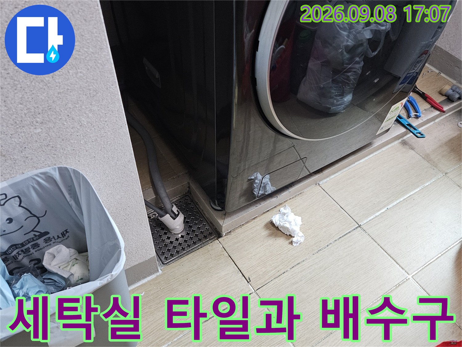 세탁실 드럼 세탁기와 하수구 배수구가 보이는 현장 사진