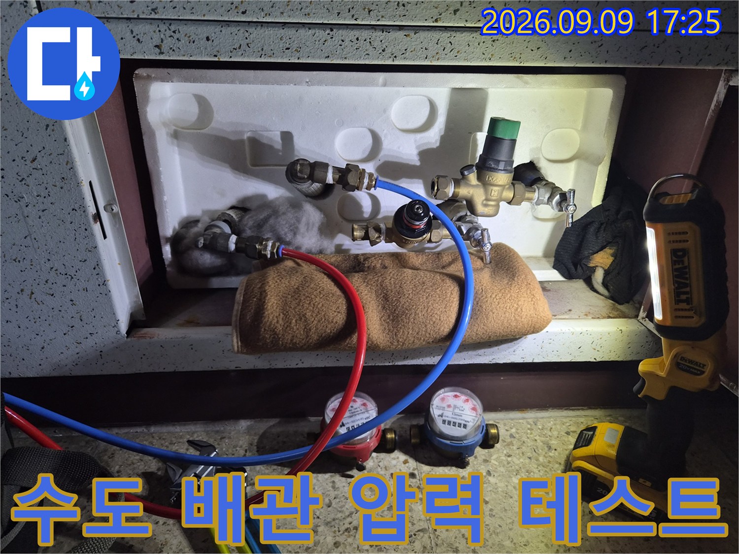 수도 계량기와 연결된 호스를 통해 배관의 기밀 상태를 점검하는 장면