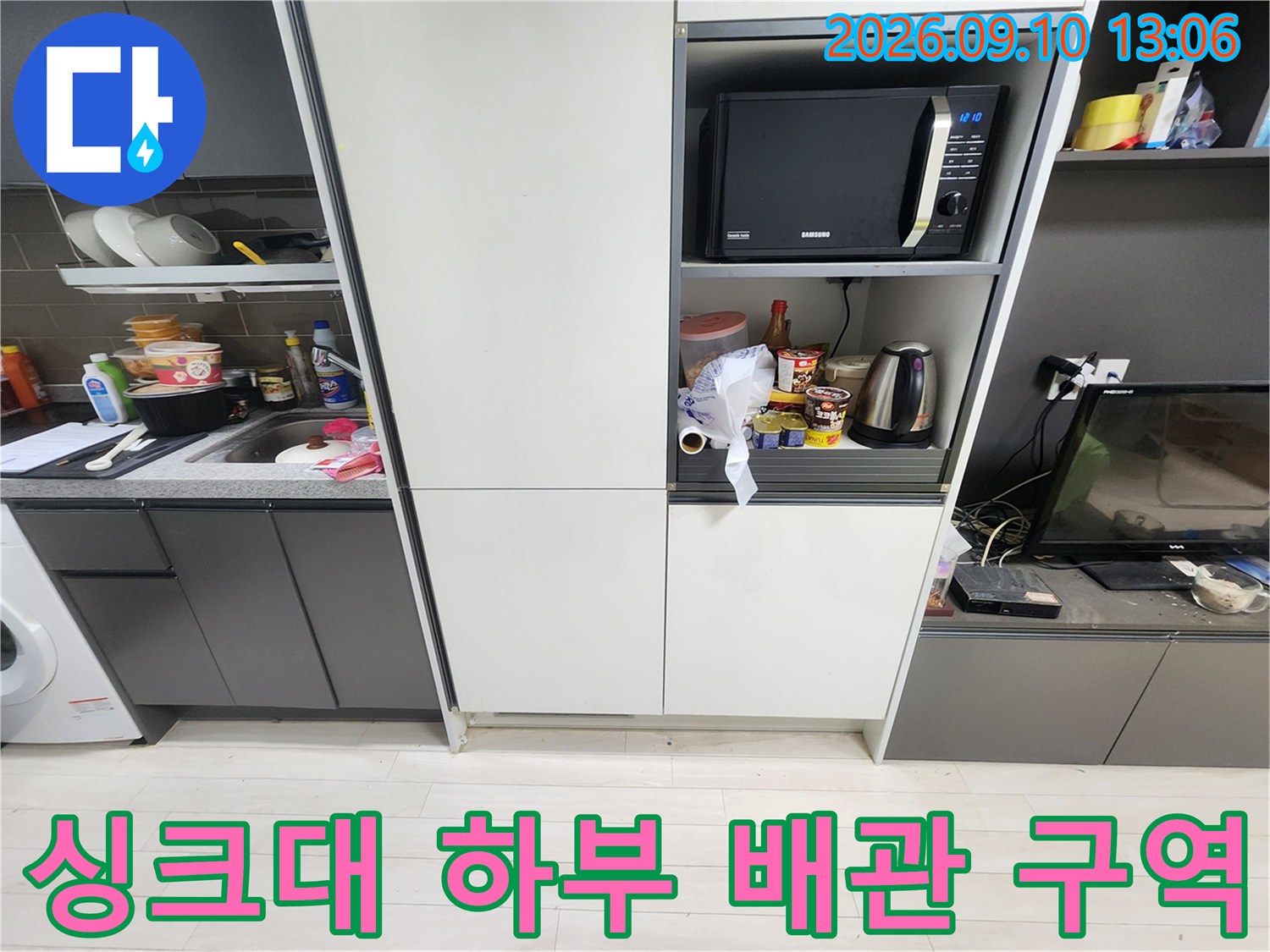 주방 싱크대 하부장과 전자레인지가 있는 누수 점검 현장 모습