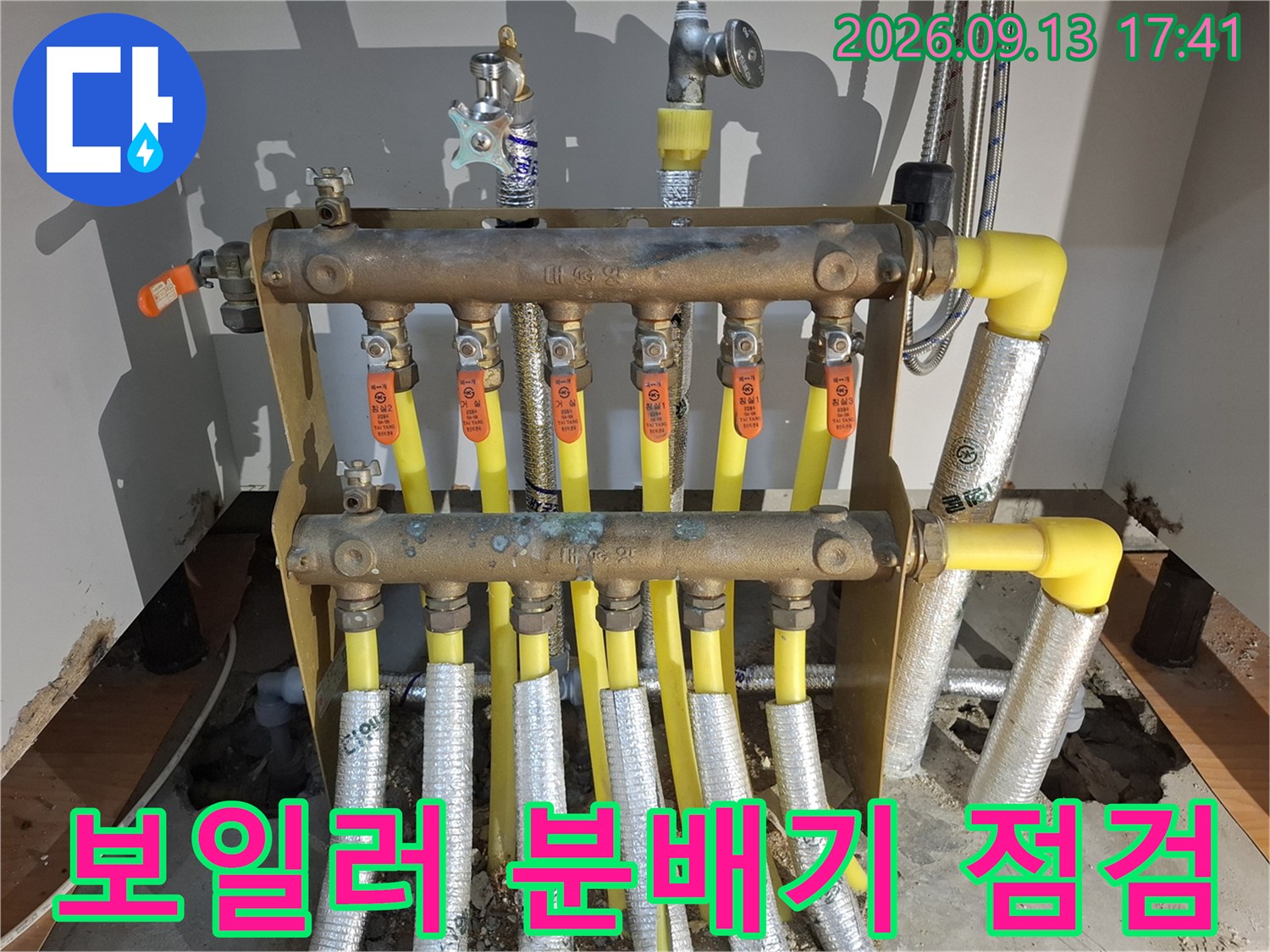 분배기 밸브와 노란색 배관이 연결된 싱크대 하부 모습