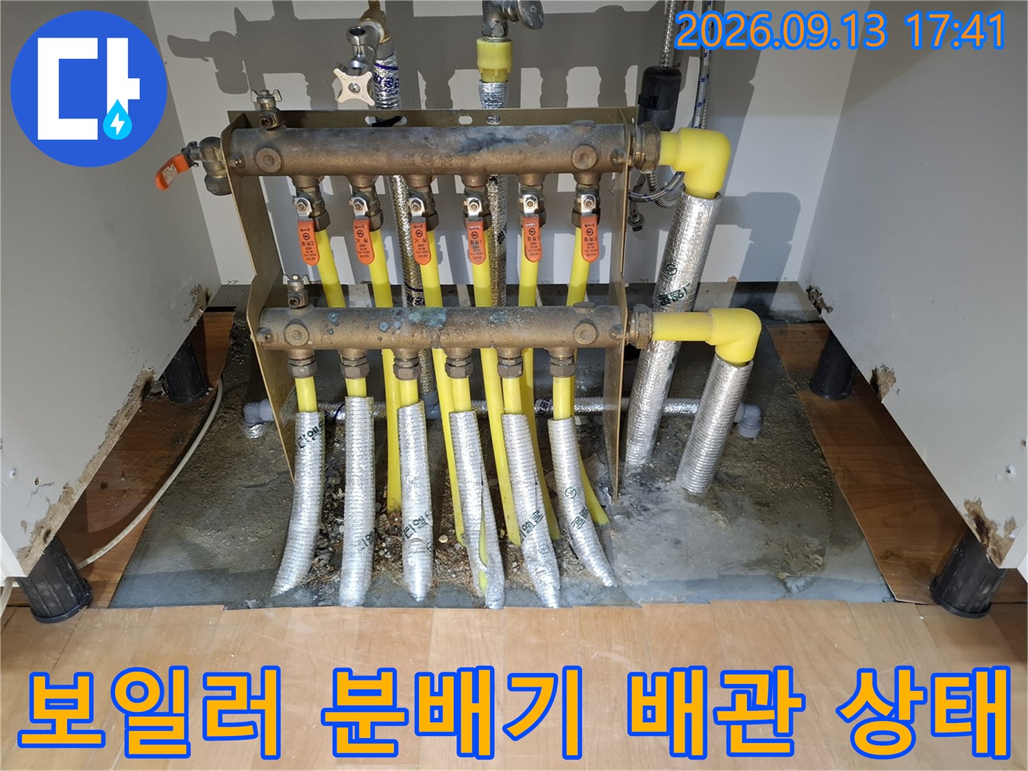 싱크대 하단에 위치한 보일러 분배기와 노란색 연결 배관의 모습입니다.