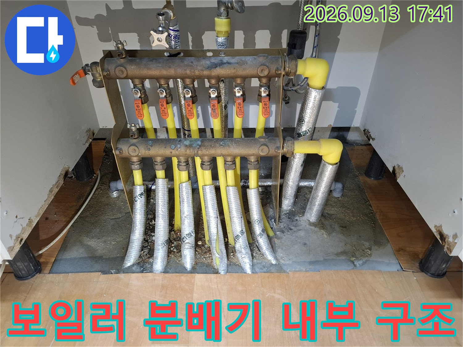 싱크대 하부 공간에 설치된 보일러 분배기와 연결 배관들의 모습입니다.
